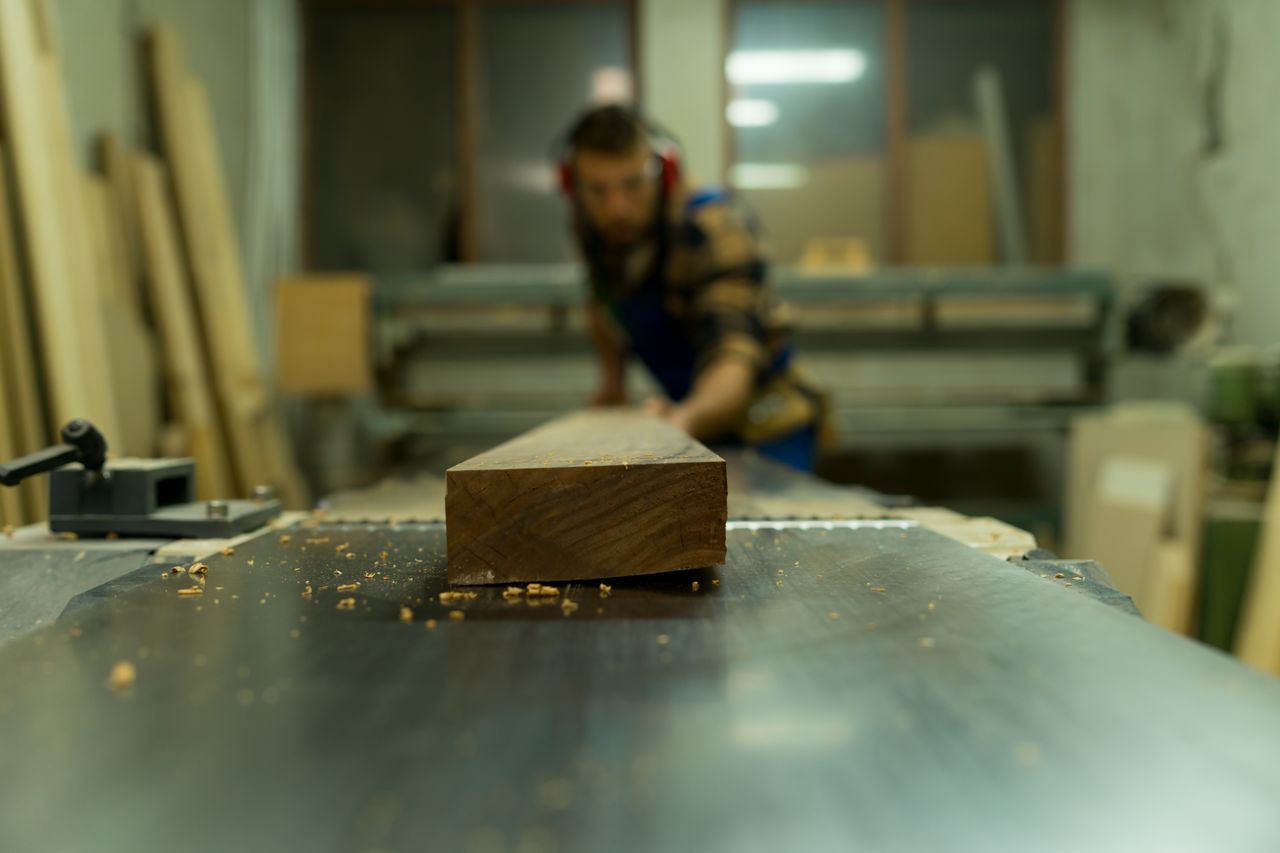 Menuisier usinant une pièce de bois massif à l'atelier