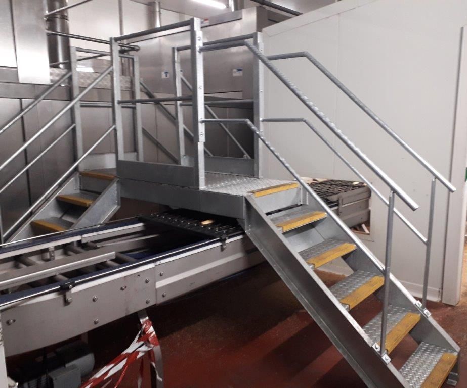 Escalier industriel en inox avec marches antidérapantes et main courante au-dessus d'un convoyeur