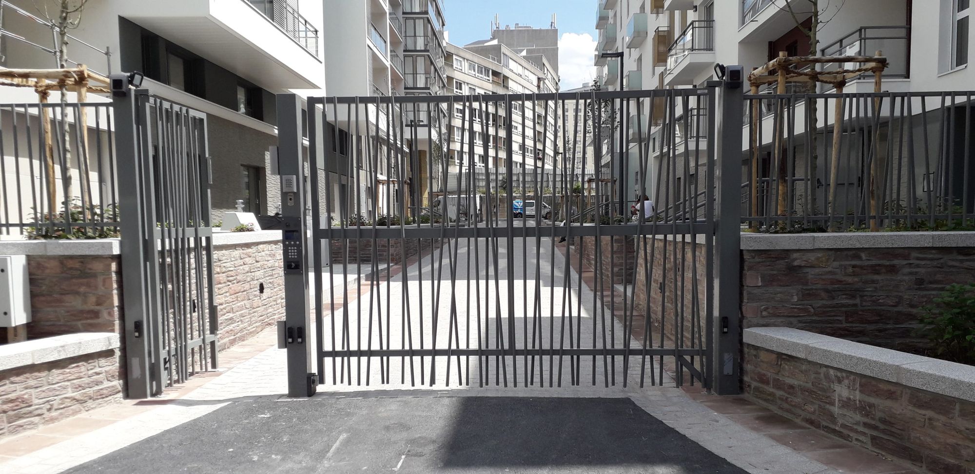 Portail industriel coulissant à barreaudage devant un bâtiment d'activité